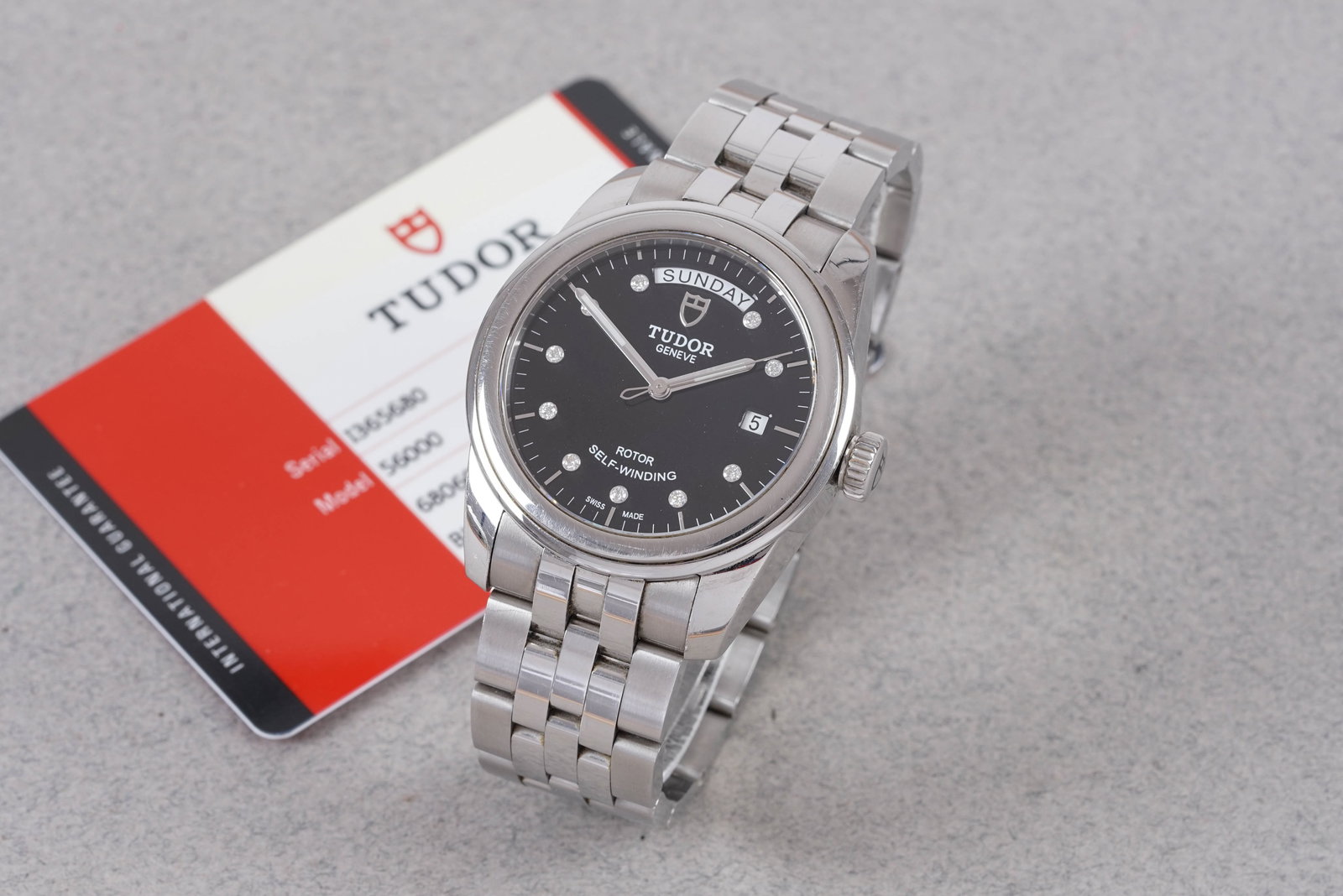 TUDOR GLAMOUR DIAMOND SET DATE DAY W/ GUARANTEE CARD REF. 56000 CIRCA 2017: This watch is a ref. 56000 and is fitted with a circular black dial with day/date windows, diamond set hour markers and baton hands. The 40 mm steel case is fitted with a tudor screw crown and a screw