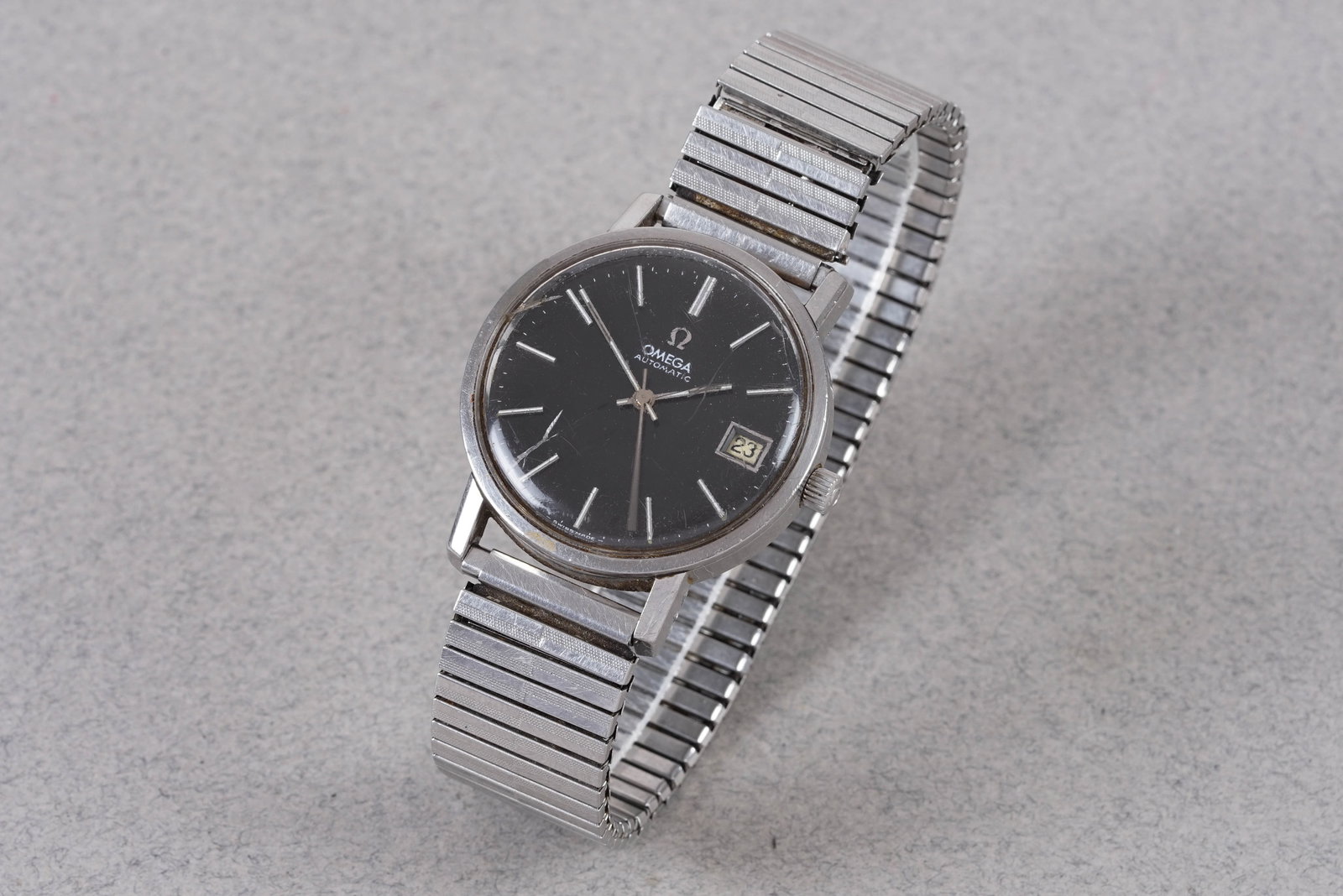 OMEGA AUTOMATIC DATE WRISTWATCH: OMEGA AUTOMATIC DATE WRISTWATCH, this watch is a ref. and is fitted with a round grey/black dial with a date window, baton hour markers and hands. The 34 mm steel case is fitted with a omega crown and