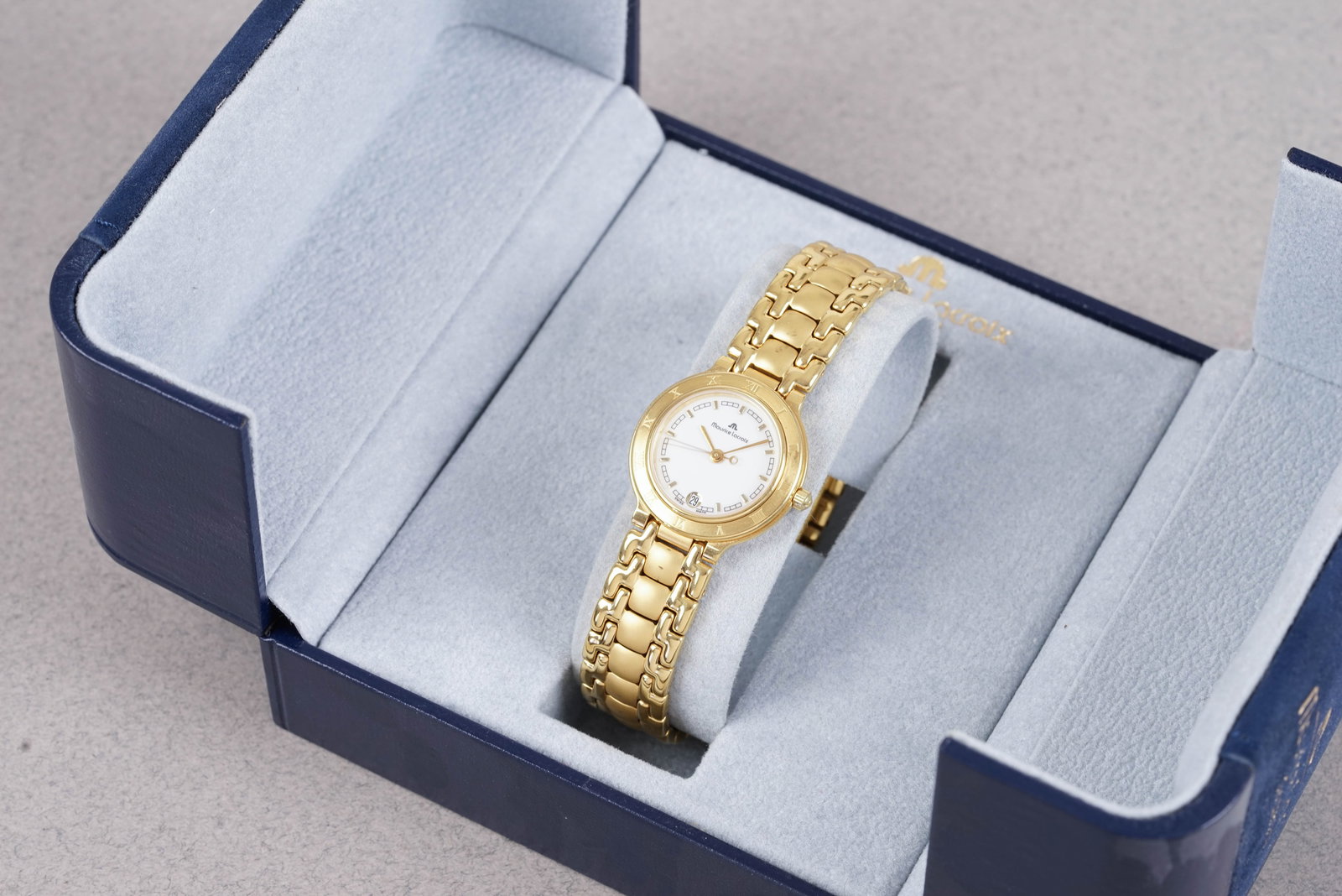 MAURICE LACROIX GOLD PLATED DATE W/ BOX REF. 75416: MAURICE LACROIX GOLD PLATED DATE W/ BOX REF. 75416, this watch is a ref. 75416 and is fitted with a circular white dial with a date window, Baton hour markers and hands. The 25mm gold plated case is
