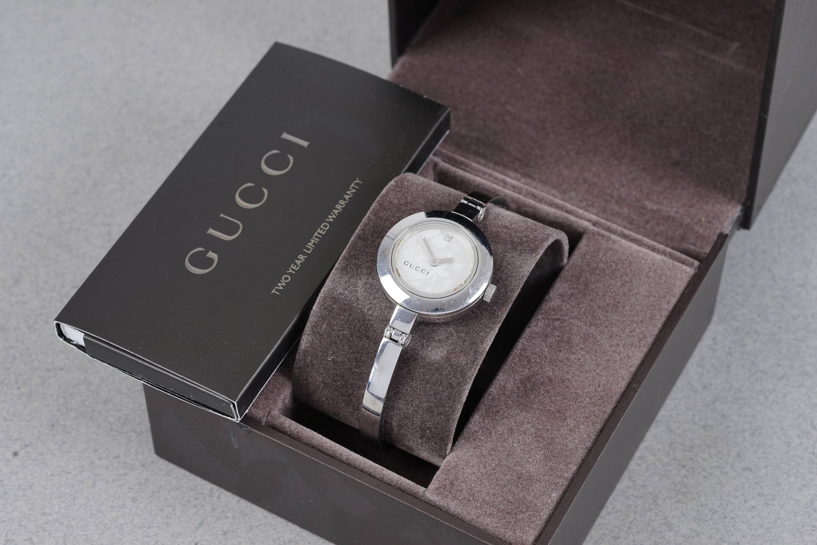 GUCCI DIAMOND DOT W/ BOX & GUARANTEE CARD REF. 105: GUCCI DIAMOND DOT W/ BOX & GUARANTEE CARD REF. 105, this watch is a ref. 105 and is fitted with a white circular dial with, single diamond hour marker at 12 and baton hands. The 25mm steel case