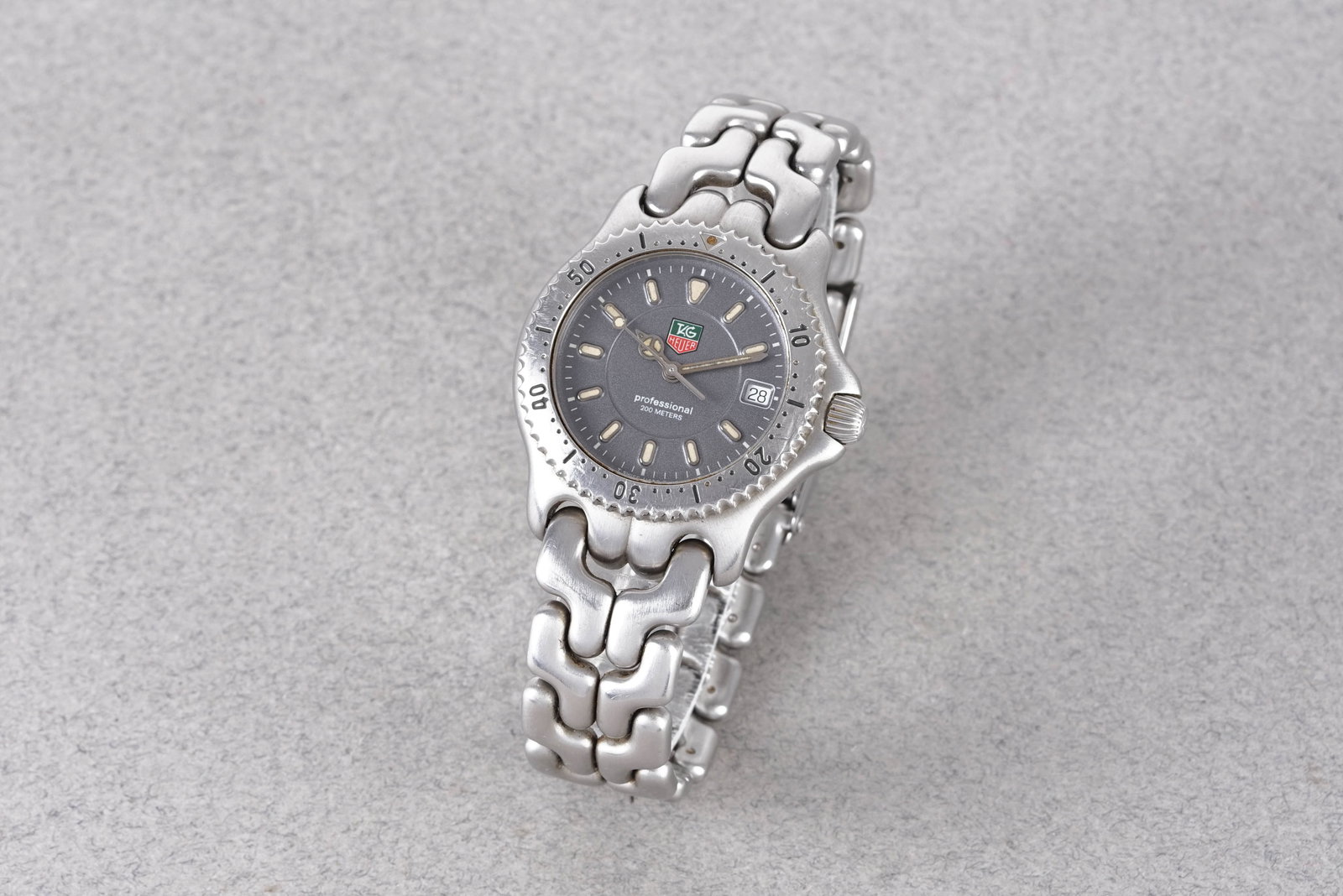 TAG HEUER PROFESSIONAL 200 METERS DATE REF. WG1213-K0: TAG HEUER PROFESSIONAL 200 METERS DATE REF. WG1213-K0, this watch is a ref. WG1213-K0 and is fitted with a circular grey dial with a date window, applied hour markers and hands. The 34mm stainless