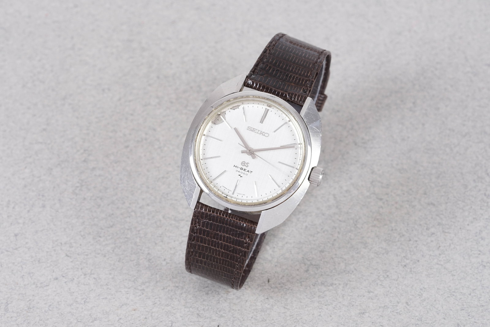 GRAND SEIKO HI-BEAT 36000 LINEN DIAL REF. 4520-7000 W/ BUCKLE: GRAND SEIKO HI-BEAT 36000 LINEN DIAL REF. 4520-7000 W/ BUCKLE, this watch is a ref. 4520-7000 and is fitted with a circular linen dial with applied hour markers and hands. The 37mm stainless steel