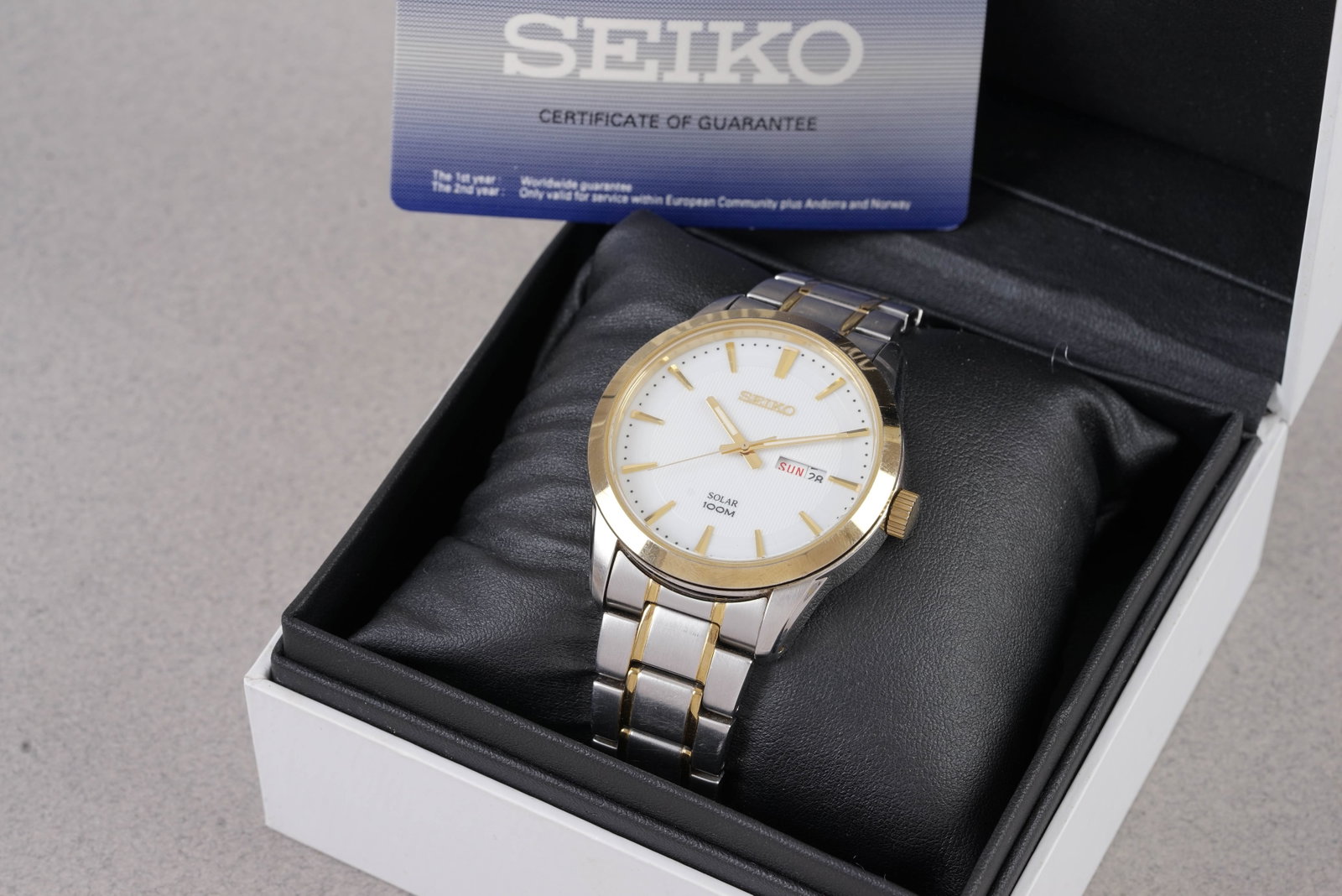 SEIKO SOLAR DAY DATE TWO TONE W/ BOX & GUARANTEE CARD REF. V158-0AS0: SEIKO SOLAR DAY DATE TWO TONE W/ BOX & GUARANTEE CARD REF. V158-0AS0,and is fitted with a white round dial with day/date window, gold tone baton hour markers and hands. The 44mm bi metal steel cas