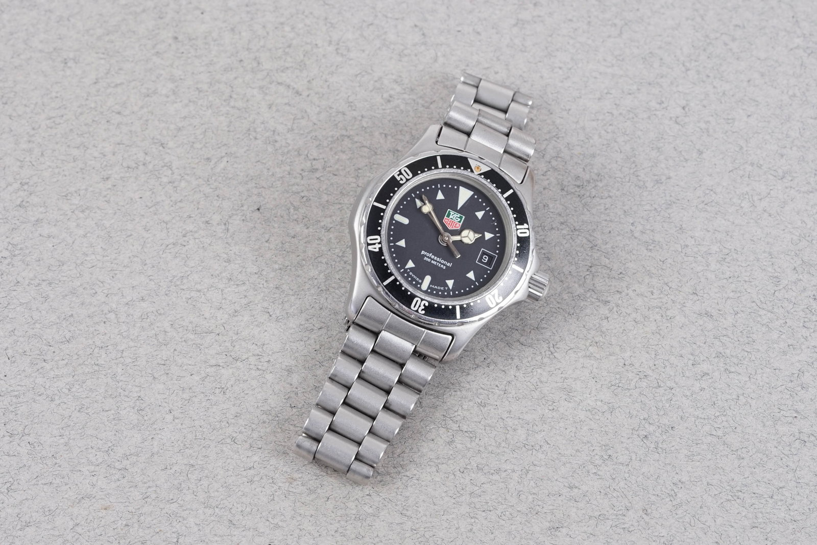 TAG HEUER PROFESSIONAL 200 REF. 973.008F: TAG HEUER PROFESSIONAL 200 REF. 973.008F, and is fitted with a circular black dial with date window, triangular hour markers and Mercedes hands. The 27mm steel case is fitted with a screw crown and ca