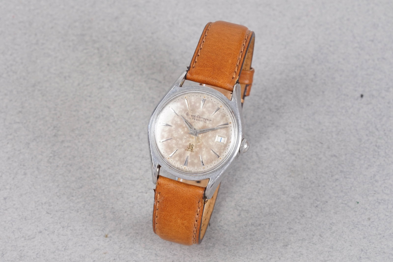 GIRARD-PERREGAUX GYROMATIC DATE REF. 6585 CIRCA 1950S: GIRARD-PERREGAUX GYROMATIC DATE REF. 6585 CIRCA 1950S, this watch is fitted with a circular patina dial with date window, dagger hour markers and hands. The 34mm steel case is fitted with a GP crown