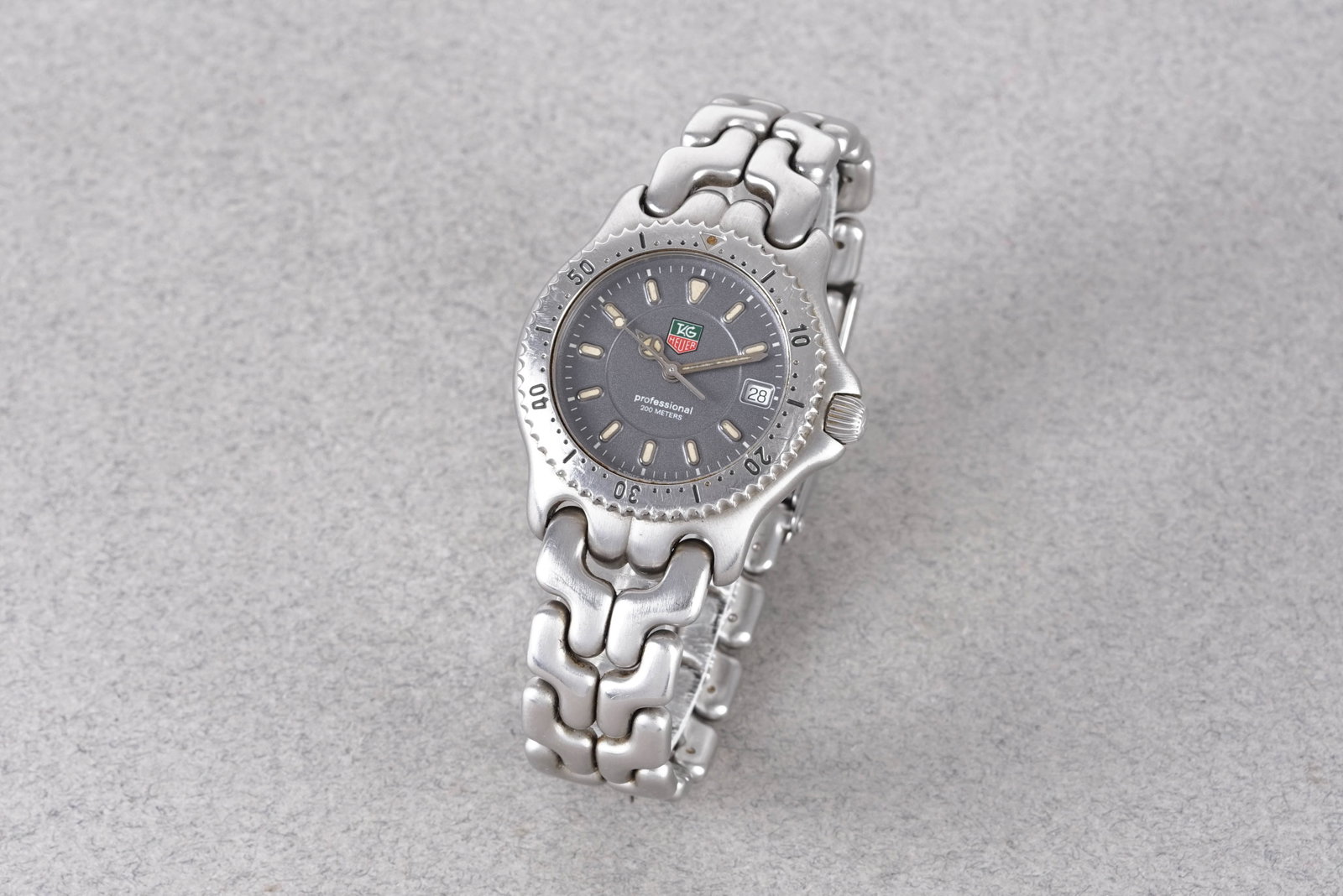 TAG HEUER PROFESSIONAL 200 METERS DATE REF. WG1213-K0: TAG HEUER PROFESSIONAL 200 METERS DATE REF. WG1213-K0, this watch is a ref. WG1213-K0 and is fitted with a circular grey dial with a date window, applied hour markers and hands. The 34mm stainless