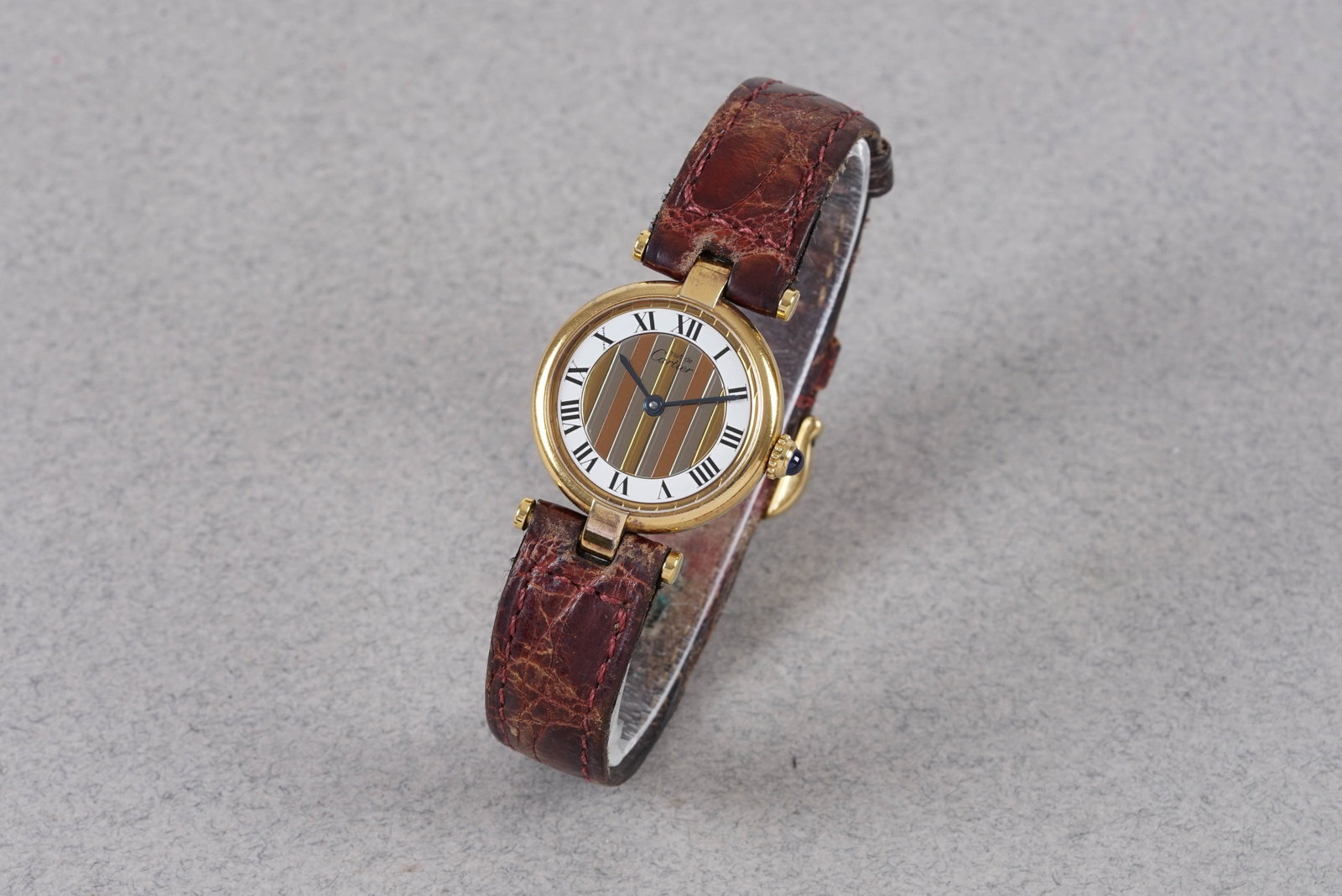 CARTIER VENDOME TRINITY GOLD VERMEIL MUST REF. 590004: CARTIER VENDOME TRINITY GOLD VERMEIL MUST REF. 590004, this watch is a ref. 590004 and is fitted with a round tricolour dial, roman numeral hour markers and blue sword hands. The 24mm gilt case is