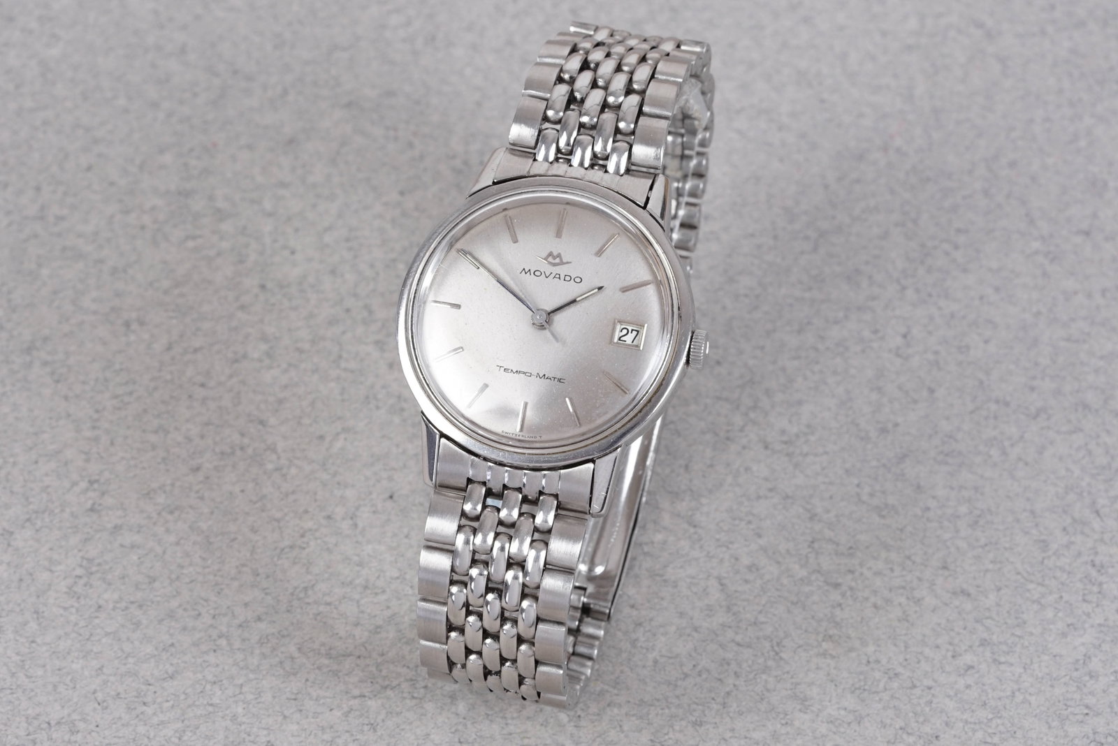 MOVADO TEMPO-MATIC DATE W/ MOVADO BRACELET: MOVADO TEMPO-MATIC DATE W/ MOVADO BRACELET, this watch is fitted with a circular white dial with date window, baton hour markers and hands. The 35mm steel case is fitted with a Movado crown and a
