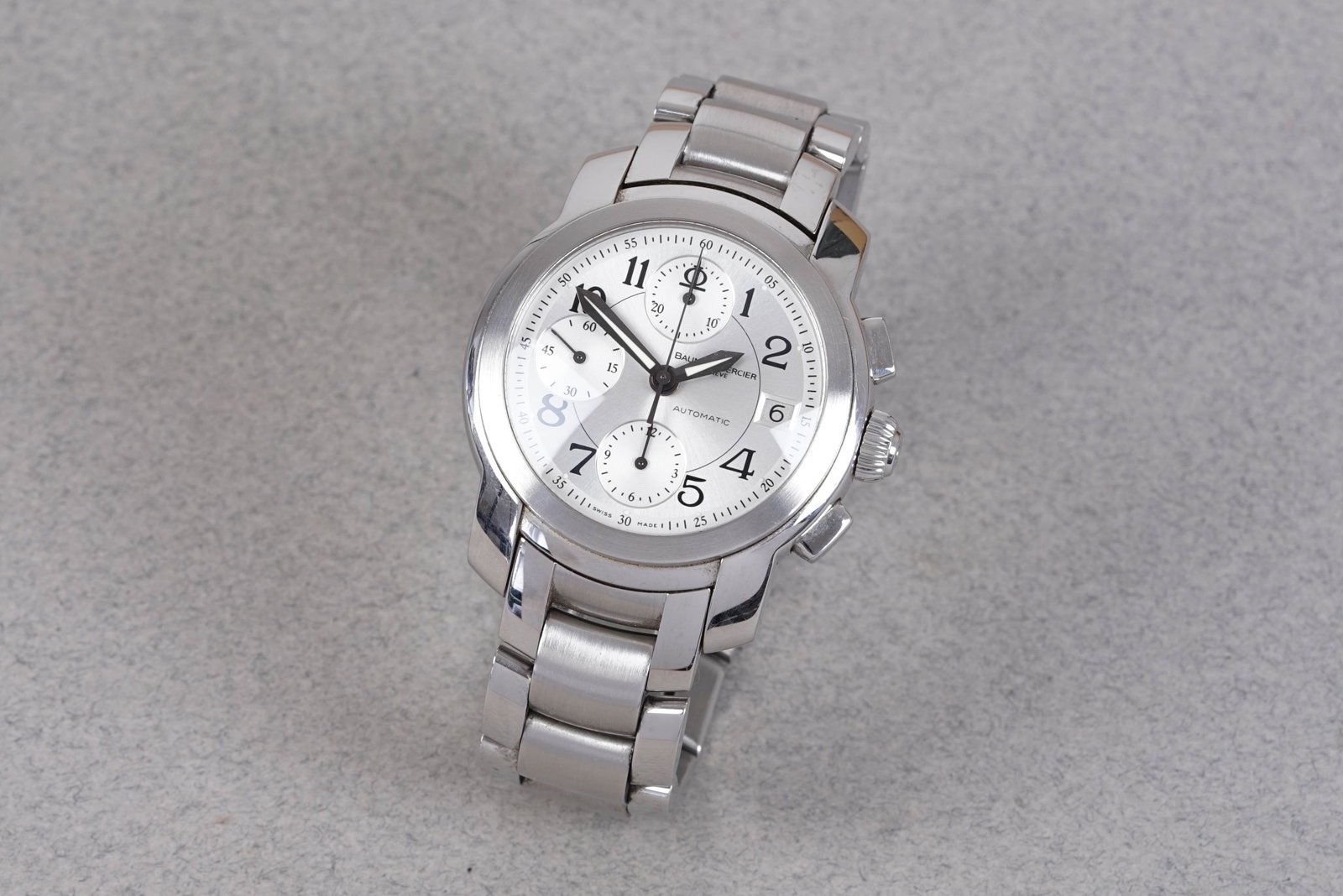 BAUME & MERCIER CAPELAND CHRONOGRAPH REF. MV045216: BAUME & MERCIER CAPELAND CHRONOGRAPH REF. MV045216, and is fitted with a circular silver dial with a date window and 3 sub dials, numerical hour markers and sword hands. The 40mm steel case is