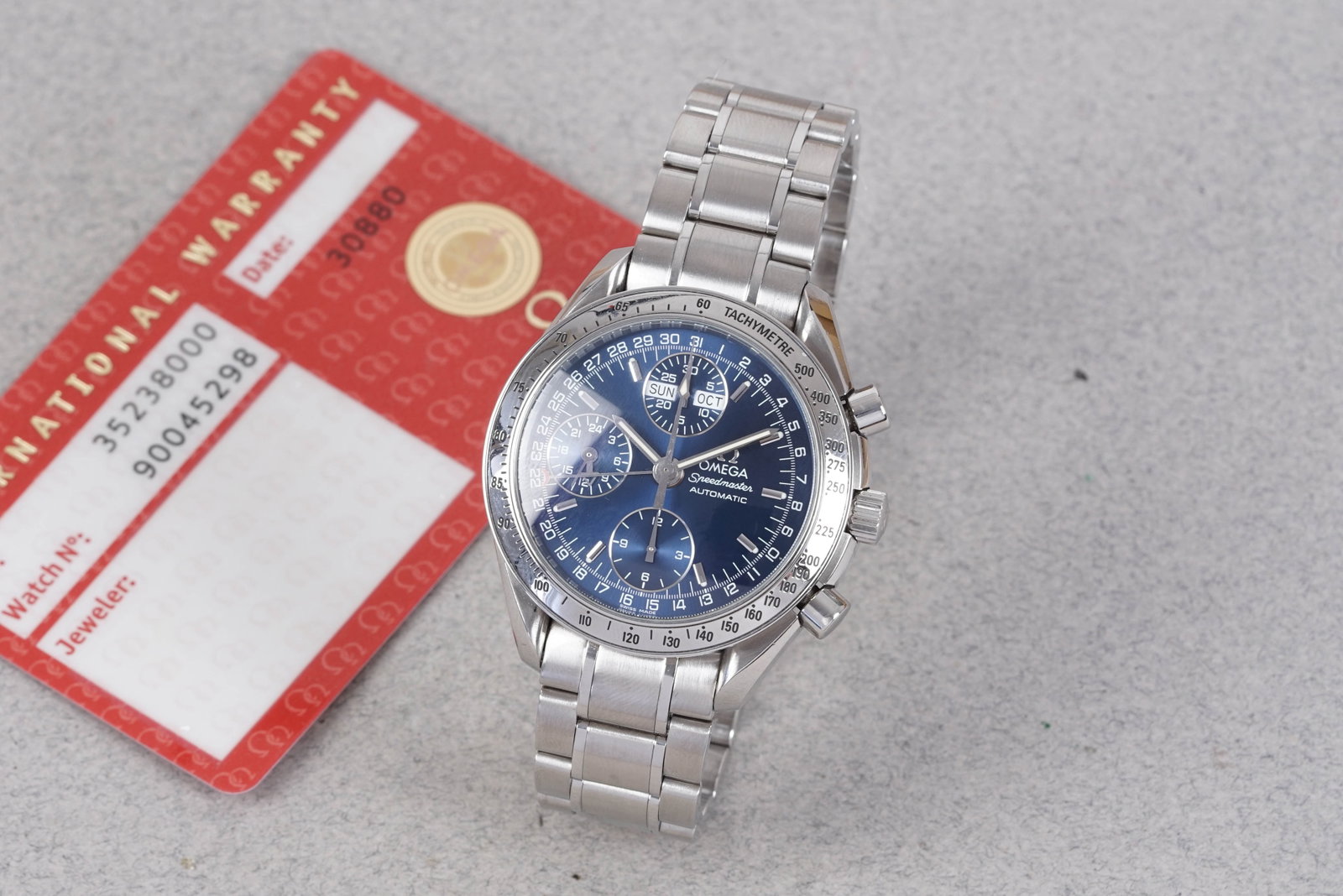 OMEGA SPEEDMASTER DAY DATE CALENDAR AUTOMATIC CHRONOGRAPH W/ GUARANTEE CARD REF. 35238000: OMEGA SPEEDMASTER DAY DATE CALENDAR AUTOMATIC CHRONOGRAPH W/ GUARANTEE CARD REF. 35238000, this watch is a ref. 35238000 and is fitted with a circular blue dial with hour markers and hands. The 39mm s