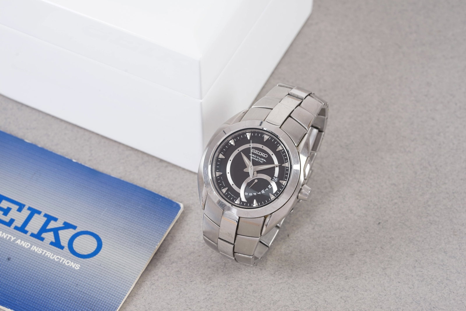 SEIKO ARCTURA KINETIC DATE W/ BOX & GUARANTEE PAPERS REF. 5M54-0AB0: SEIKO ARCTURA KINETIC DATE W/ BOX & GUARANTEE PAPERS REF. 5M54-0AB0, this watch is a ref. 5M54-0AB0 and is fitted with a round black dial with a date window and day sub dial, dagger hour markers