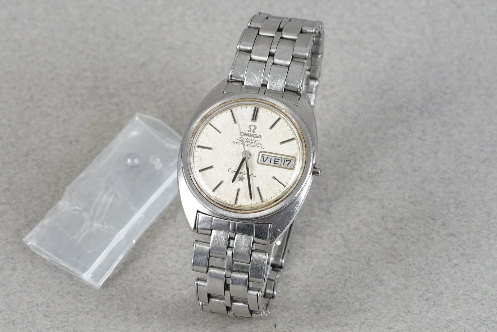 OMEGA CONSTELLATION LINEN DIAL AUTOMATIC CHRONOMETER DAY DATE WRISTWATCH: OMEGA CONSTELLATION LINEN DIAL AUTOMATIC CHRONOMETER DAY DATE WRISTWATCH DIAL: Circular patina dial, stick hour markers, day date window CASE: 35mm stainless steel, screw down case back MOVEMENT: Auto