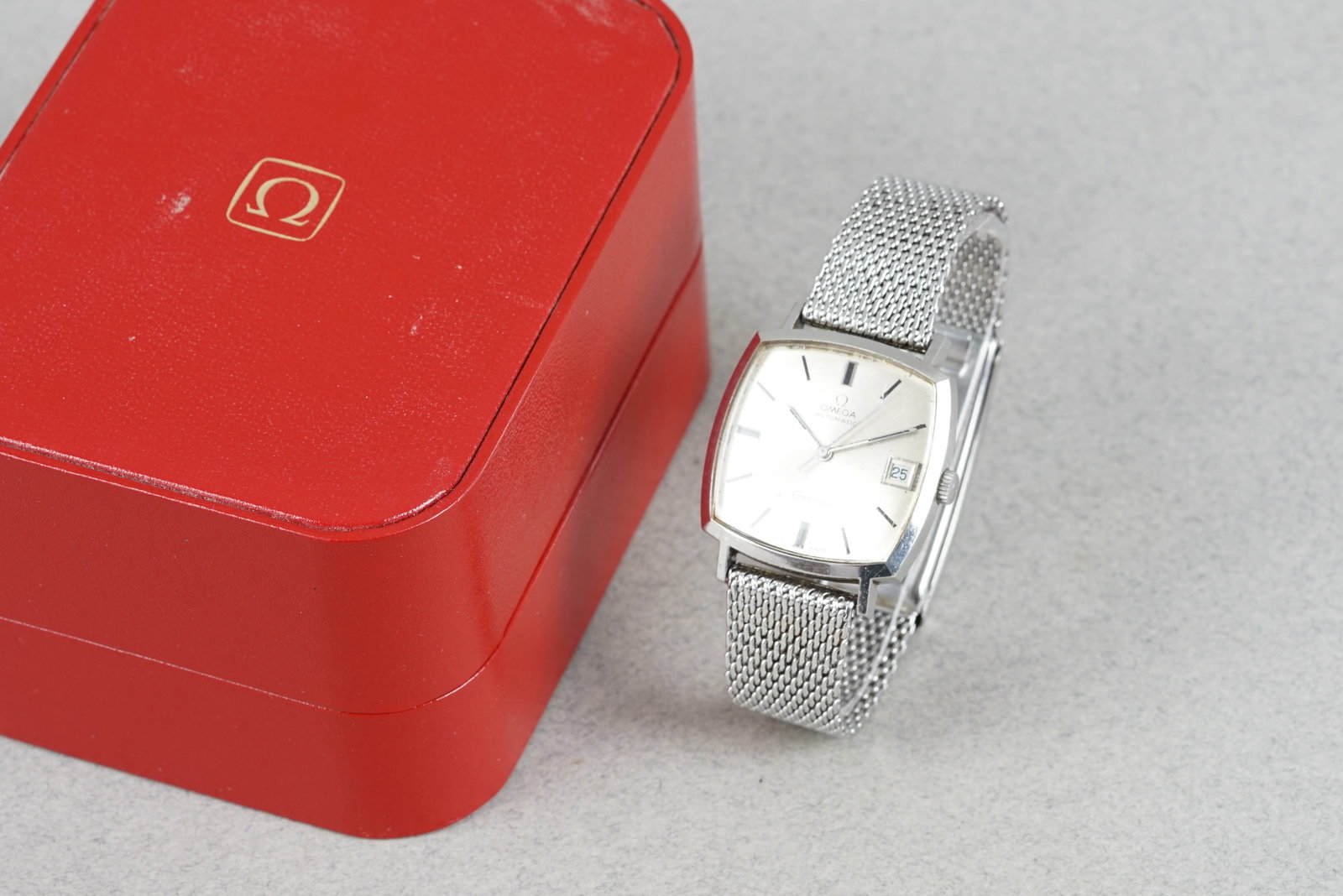 OMEGA AUTOMATIC GENEVE DATE WRISTWATCH W/ BOX: OMEGA AUTOMATIC GENEVE DATE WRISTWATCH W/ BOX DIAL: Square silver dial, black stick hour markers, date window CASE: 32mm stainless steel, omega crown, snap case back MOVEMENT: Automatic omega BRACELET
