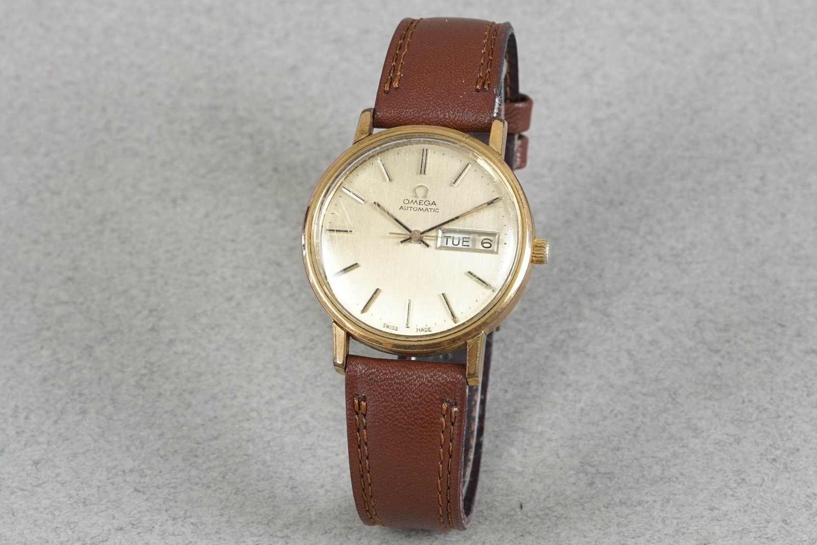 OMEGA AUTOMATIC GOLD PLATED DAY DATE WRISTWATCH: OMEGA AUTOMATIC GOLD PLATED DAY DATE WRISTWATCH DIAL: Brushed champagne dial, stick hour markers and hands, day date windows CASE: 34mm gold plated with omega crown, snap case back MOVEMENT: