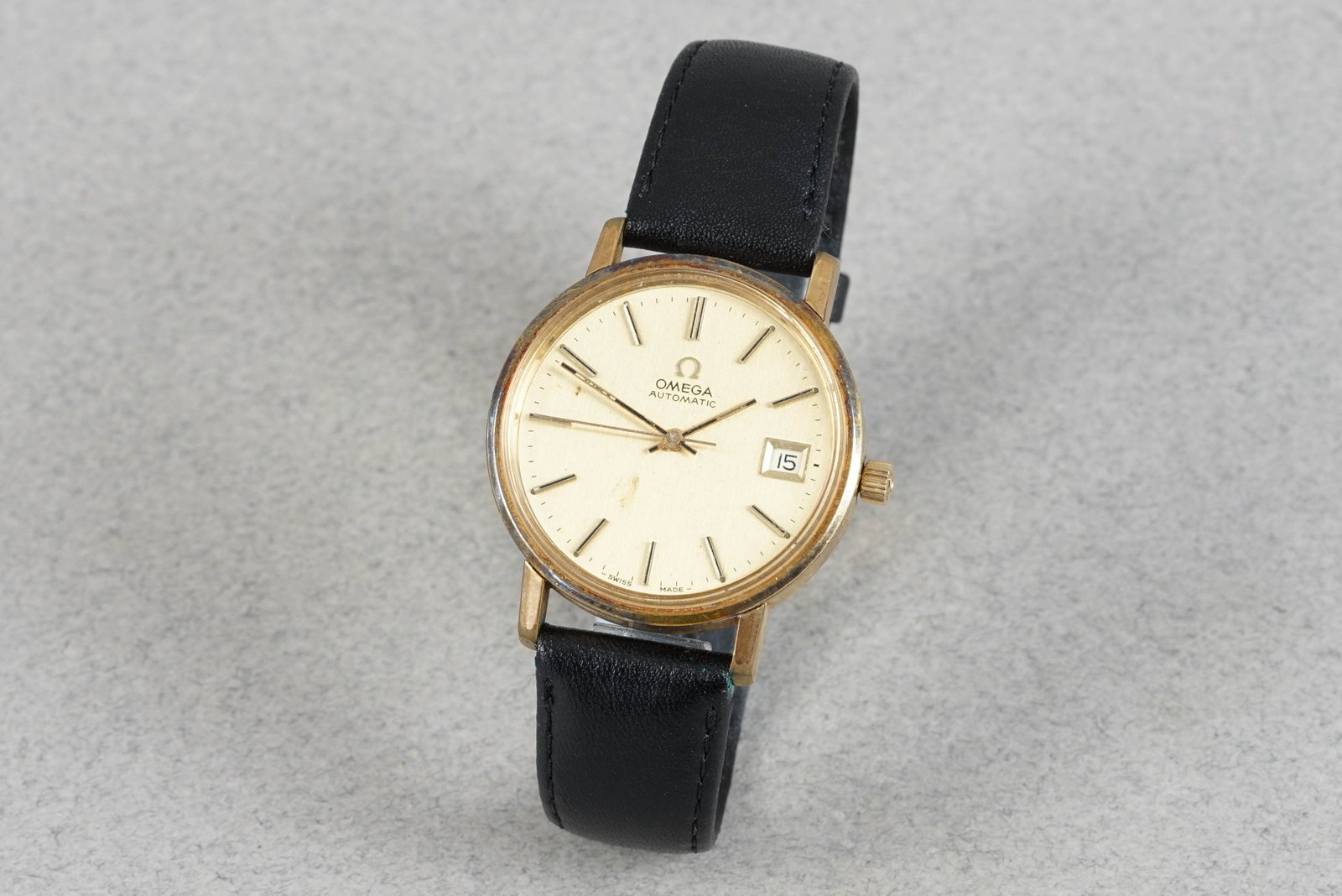 OMEGA AUTOMATIC DATE GOLD PLATED WRISTWATCH: OMEGA AUTOMATIC DATE GOLD PLATED WRISTWATCH DIAL: Champagne dial with stick hour markers and hands, date window CASE: Gold plated 35mm w omega crown and snap case back MOVEMENT: Automatic omega