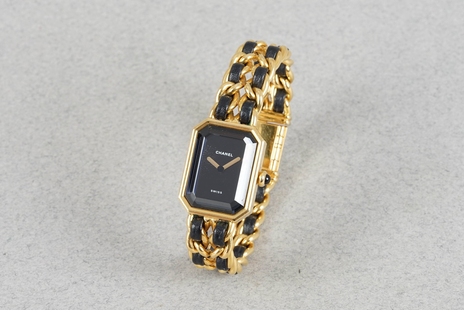 CHANEL PREMIÈRE M BRACELET WRISTWATCH H0001 MS05056: CHANEL PREMIÈRE M BRACELET WRISTWATCH H0001 MS05056 DIAL: Rectangular black dial with gold hands CASE: 20x26 gold plated case MOVEMENT: Quartz movement BRACELET OR STRAP: Goad plated and leather