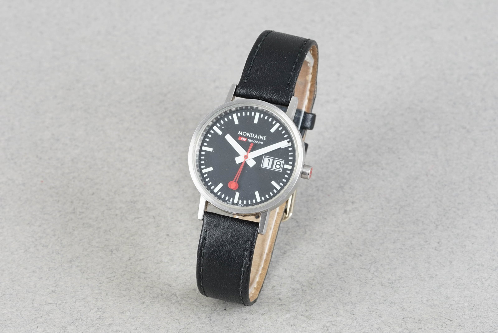 MONDAINE RAILWAY QUARTZ REF. 30008: MONDAINE RAILWAY QUARTZ REF. 30008 DIAL: Circular black dial, white hour makers, date window CASE: 32mm stainless steel case MOVEMENT: Quartz BRACELET OR STRAP: Leather strap ACCESSORIES: N/A