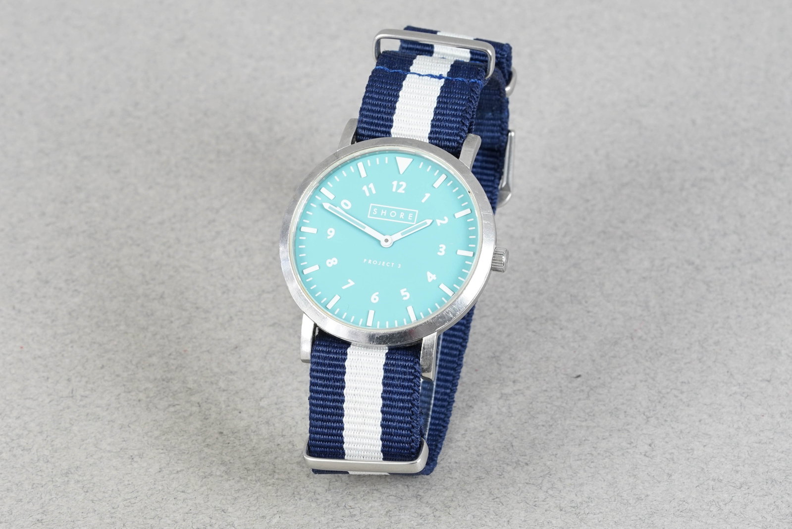 SHORE PROJECT 3 QUARTZ WRISTWATCH: SHORE PROJECT 3 QUARTZ WRISTWATCH DIAL: Circular light blue dial, white hour markers CASE: 39mm stainless steel case, screw down case back MOVEMENT: Quartz movement BRACELET OR STRAP: Nato strap