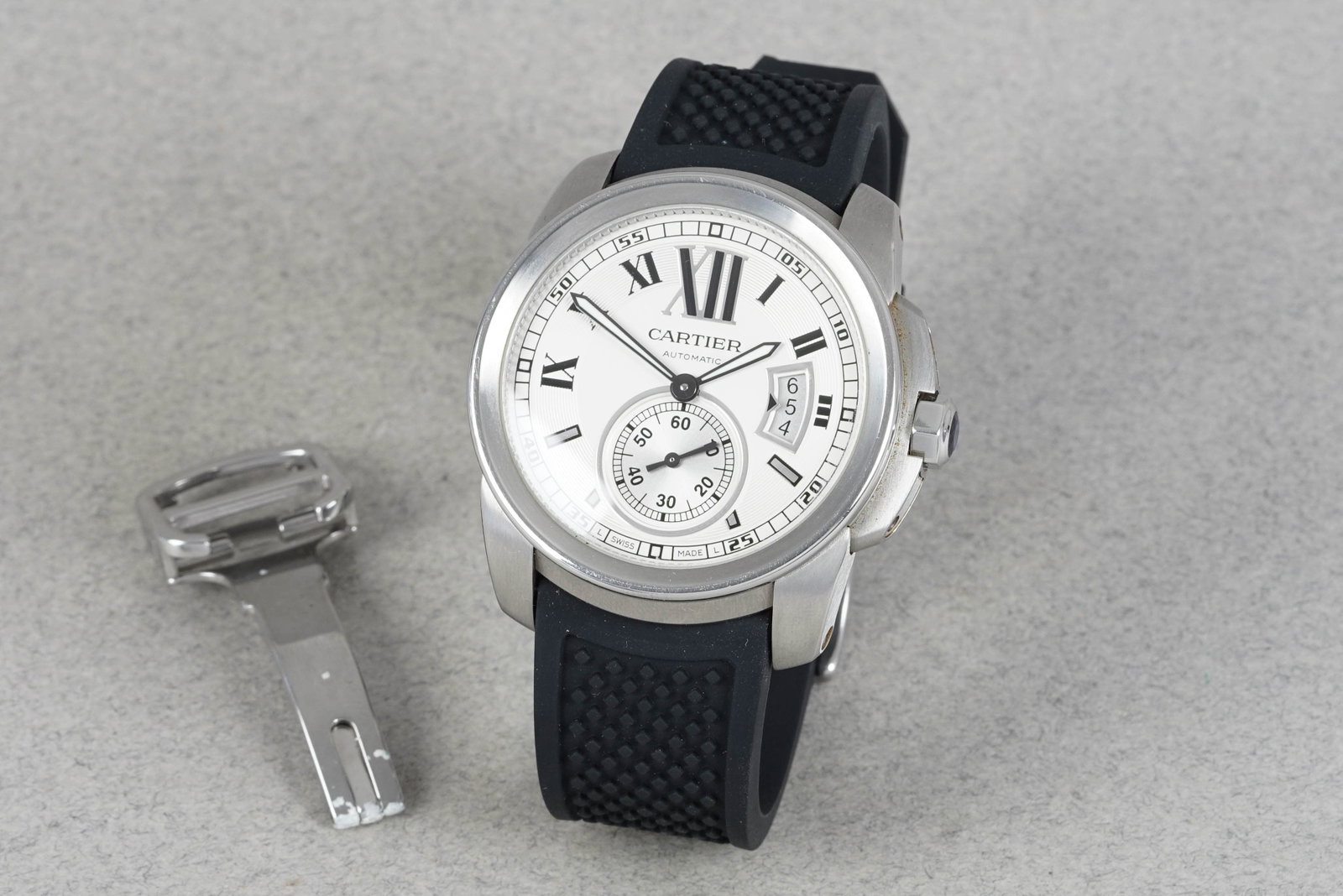 CARTIER CALIBRE DE CARTIER W/ BOX REF. W7100037: CARTIER CALIBRE DE CARTIER W/ BOX REF. W7100037, this watch is fitted with a circular white dial with sub seconds and date window, roman numeral mixed hour markers and sword hands. The 42mm steel
