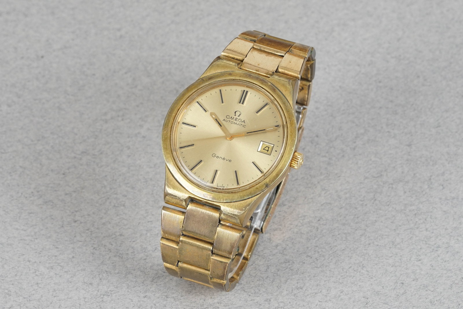 OMEG GENEVE AUTOMATIC DATE GOLD PLATED WRISTWATCH: OMEGA GENEVE AUTOMATIC DATE GOLD PLATED WRISTWATCH DIAL: Dial with applied indices, date window, hands with Lume CASE: 34mm gold plated stainless steel, screw-down case back MOVEMENT: Automatic,
