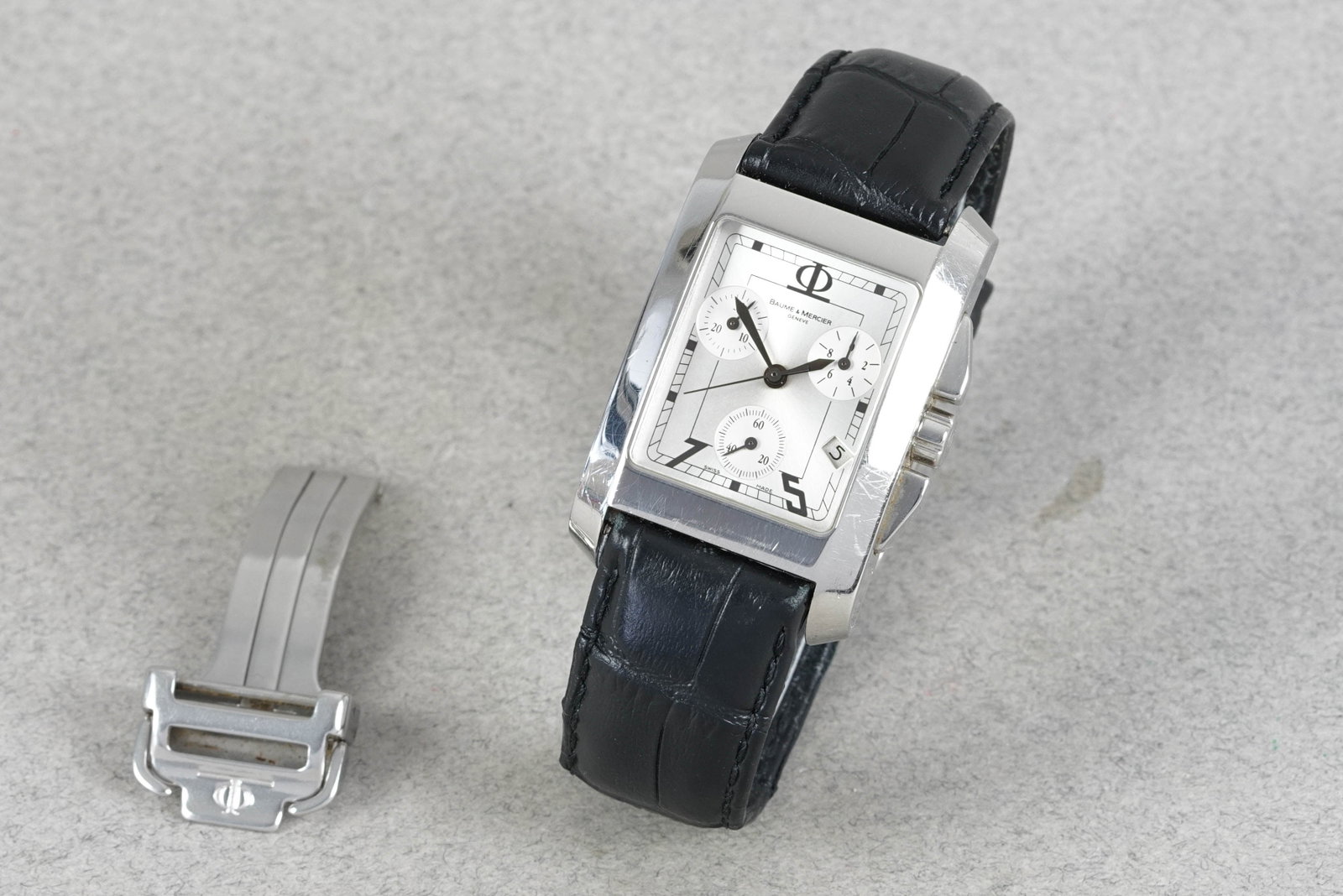 BAUME & MERCIER HAMPTON CHRONOGRAPH W/ BOX & GUARANTE CARD: BAUME & MERCIER HAMPTON CHRONOGRAPH W/ BOX & GUARANTE CARD DIAL: Rectangular silver triple register dial, date window CASE: 28.5x44mm stainless steel, crown two pushers MOVEMENT: Quartz