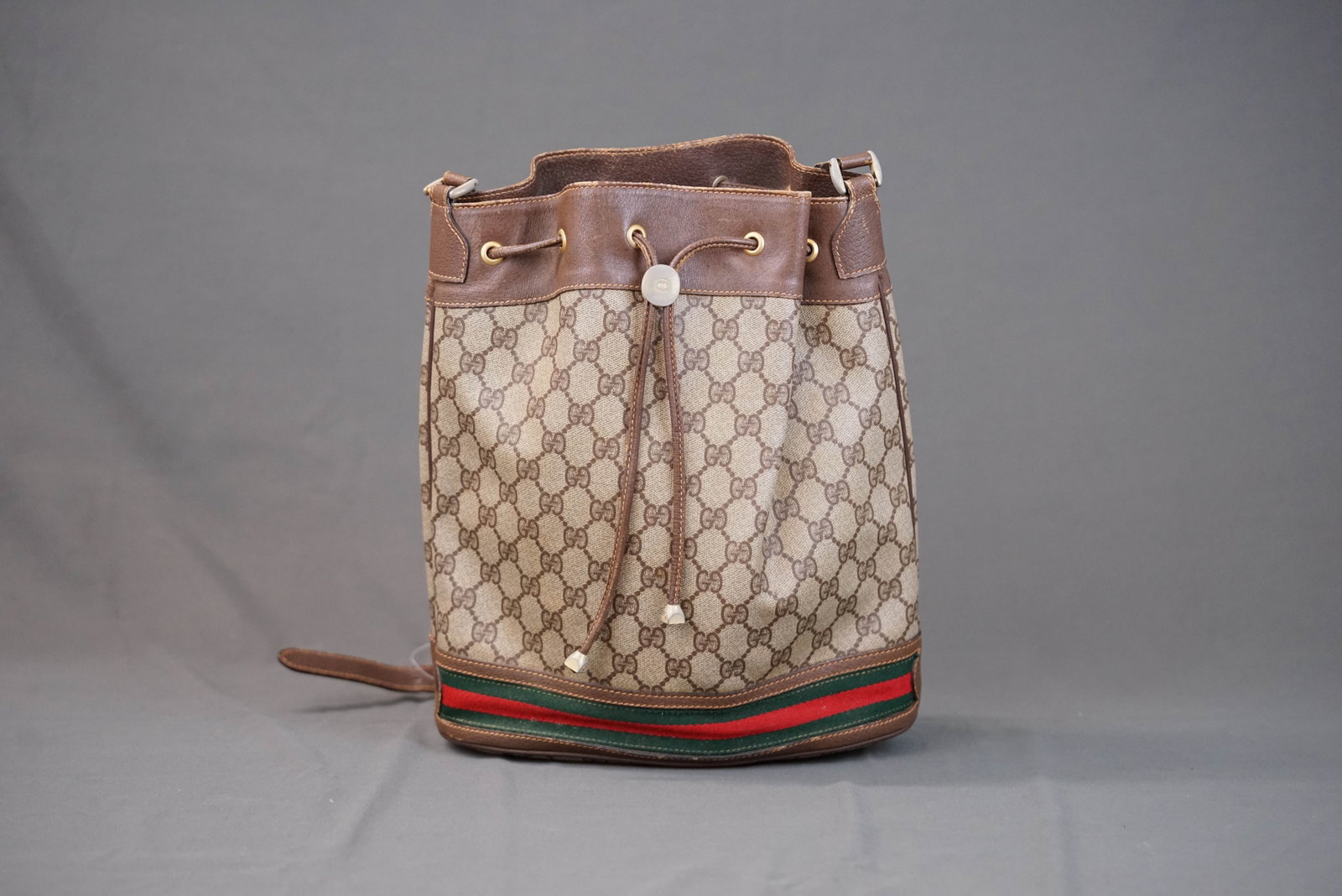GUCCI BROWN SHOULDER BAG 085: GUCCI BROWN SHOULDER BAG 085 DIMENSIONS: Width 26cm, height 30cm, depth 12cm COLOUR: brown MATERIAL: canvas, leather trim ACCESSORIES: n/a CONDITION RANK: scuffs to leather trim, general wear. If you