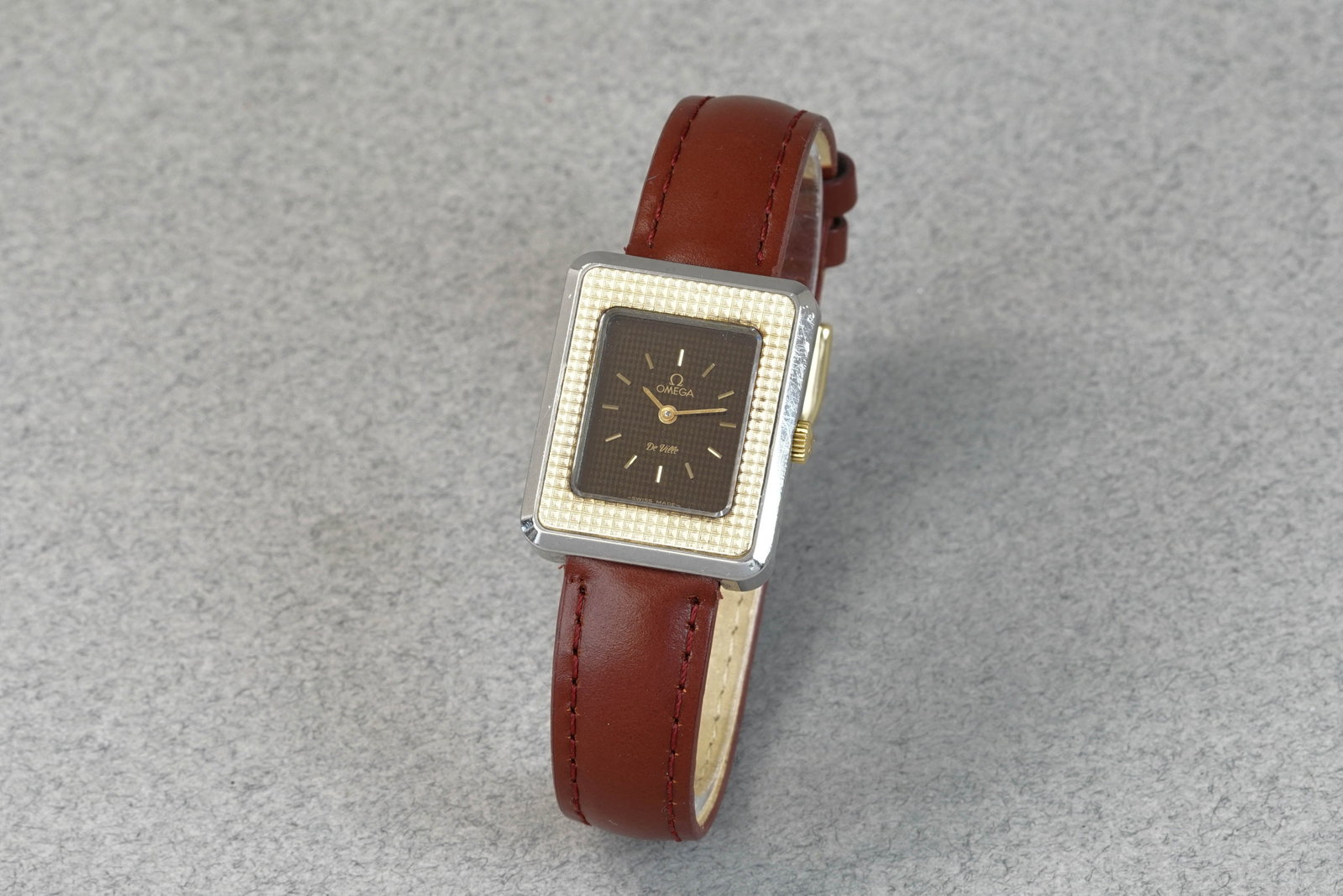 OMEGA DE VILLE BI-METAL TANK WRISTWATCH: OMEGA DE VILLE BI-METAL TANK WRISTWATCH DIAL: rectangular black dial, gilt baton hands and hour markers CASE: 24mm steel case, gold? bezel, omega crown MOVEMENT: manual wind movement running BRACELET