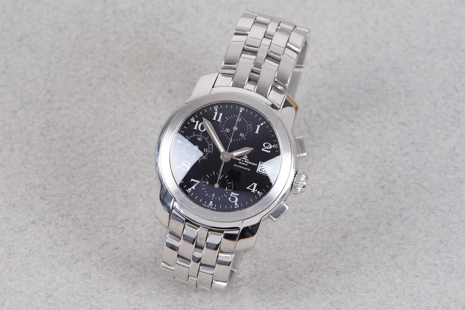 *NO RESERVE* BAUME & MERCIER CAPELAND CHRONOGRAPH W/ BOX REF. MV045216: BAUME & MERCIER CAPELAND CHRONOGRAPH W/ BOX REF. MV045216, and is fitted with a black circular dial with date window nd 3 sub dials, Breguet hour markers and sword hands. The 40mm steel case is
