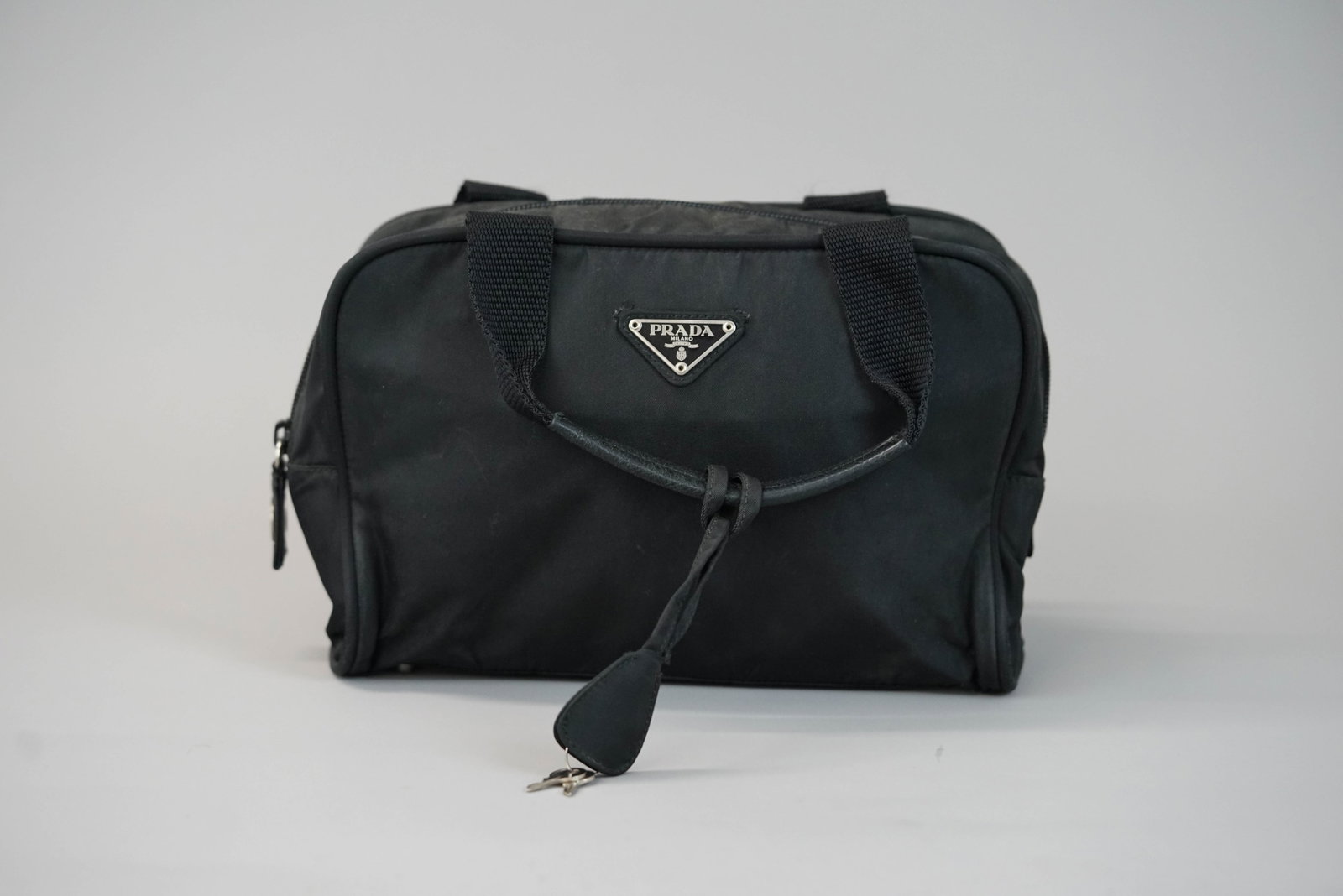 PRADA BLACK NYLON HANDBAG: PRADA BLACK NYLON HANDBAG DIMENSIONS: Width 26cm, height 17cm, depth 7cm COLOUR: Black MATERIAL: Nylon ACCESSORIES: n/a CONDITION RANK:BC If you have any questions regarding this lot please contact