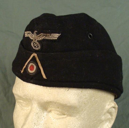 WWII German Army Panzer Enlisted Man EM Overseas Cap: This is a WW II era Panzer enlisted man's overseas cap. It is black with tan lining, and features an iron eagle patch, and black threading. The Waffenfarbe has faded from pink to white from wear. The 