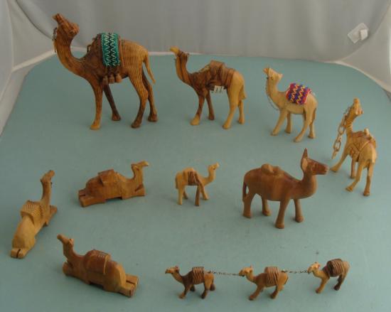 12 Wooden Camels Figurines Olive Wood Israel, Kenya: Here are a dozen nice wooden camels, all with packs except for one. Two have woven saddles, and the large one has water canteens. Three small ones form a group connected with a metal chain. They measu