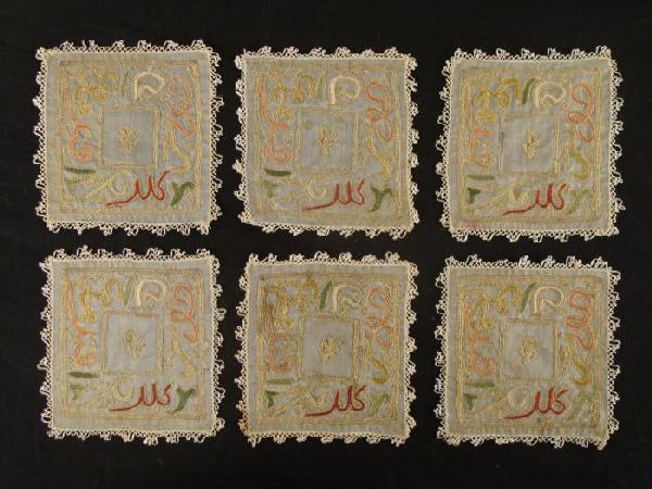 6 Early 20th Century Gold Threaded Doilies Coasters: These 6 coasters are adorned with colorful patterns bordered in genuine gold threading. The designs resemble Indian characters. Each is 4 1/2 inches square, or 5 inches including the white threaded bo