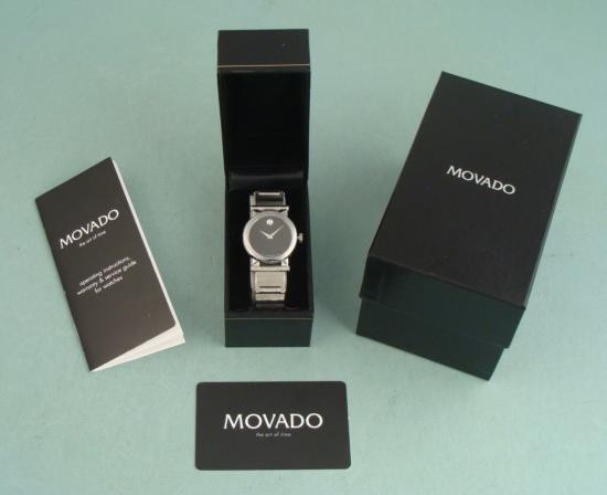 Movado Vizio Mens Black Stainless Modern Watch In Box: This Movado men's wristwatch is the Vizio model. It is a stylish modern watch, with a face reflective of their famous Museum Watch. Dial: Black, with shiny chrome dauphine pitched hands, and chrome do