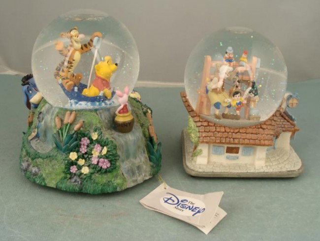 2 Disney Musical Snow Globes: Pinocchio Winnie the Pooh: These two snow globes feature some favorite Disney characters, and songs as well. One is from Winnie the Pooh, and it features a rainy scene with Tigger and Pooh riding in an overturned umbrella-- jus