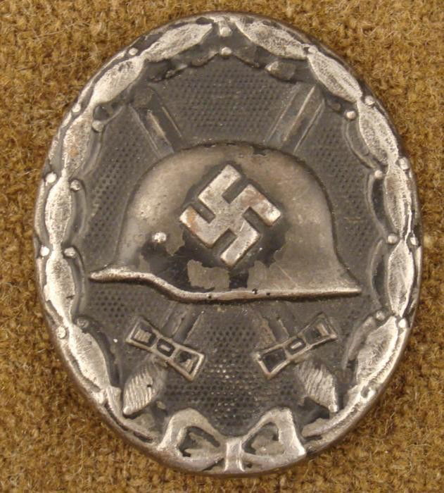 WWII Nazi Black Wound Badge Pin Back Pressed Metal: This is a WWII era Nazi Black Wound Badge. It is hollow backed pressed metal showing crossed swords, and helmet with swastika. The back has a maker mark number 88. The size is 1 1/2" x 1 3/4". It is i