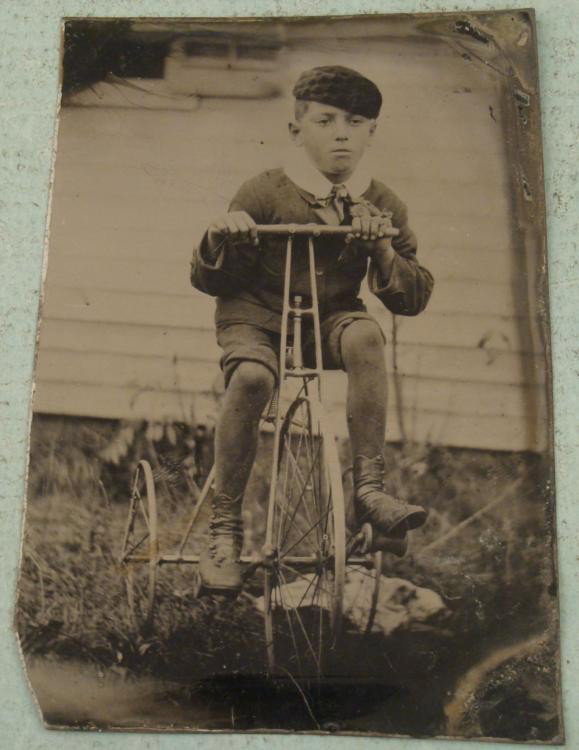 Antique Tintype Boy on Tricycle Outdoor Bike Bicycle: This antique tintype shows a boy on his big tricycle bike outside his home. The shot is very clear and in focus. The sheet is about 2" x 3". It has light wear, mostly corner wear. Most tricycle shots 