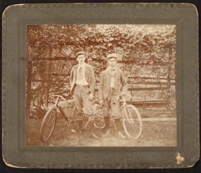 2 Delivery Boys Bicycles Bikes Orig Cabinet Card Photo: This original antique cabinet card style photograph portrays two young men outdoors with their bicycles. These might be delivery boys, judging from the strapped carrying case on the inner frame on