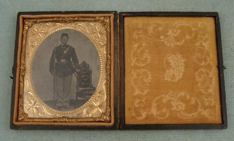 Antique Ambrotype Photo in Frame Soldier (Civil War?): Here is a photographic portrait of a soldier in uniform with rifle standing by his side, and dagger. He may be from the Civil War era, or from a militia group. The photo has some crazing and surface p