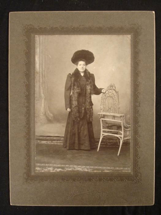 Elegant Woman in Furs and Hat Antique Photograph 1880s: This photograph portrays an elegant woman draped in furs, and wearing a large elegant hat. She is standing proudly next to a rattan chair, dressed not unlike the "unsinkable" Molly Brown, and it dates