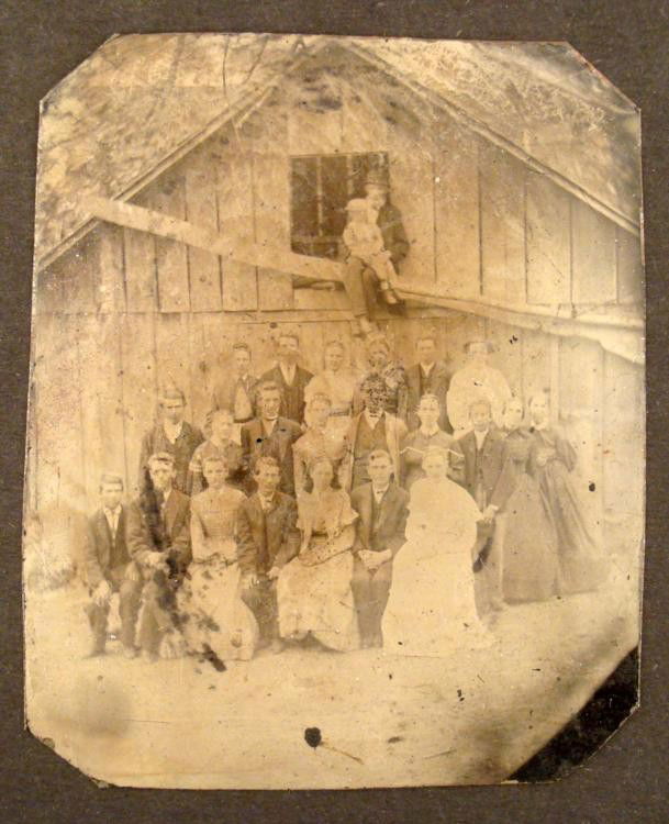 Antique Tintype Photo 24 People Large Group by Barn: This antique tintype photograph was taken outdoors in front of a rustic house or barn, and it captures a large group of 24 people. It is a great pose, with men and women, and grandad and granddaughter