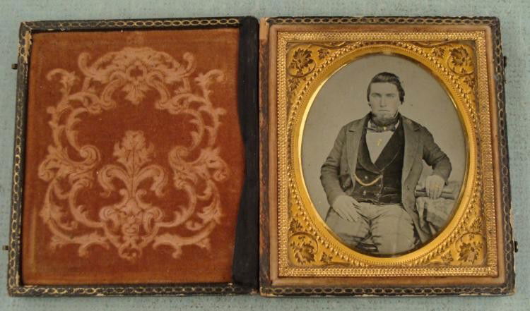 Antique Daguerreotype Photo Man Gold Embellished, Frame: This Daguerreotype portrait of a man has plenty of gold painted embellishments, on his rings, watch chain, and couple spots on his chest. It also has rose tinted cheeks. There is an embossed gold tone