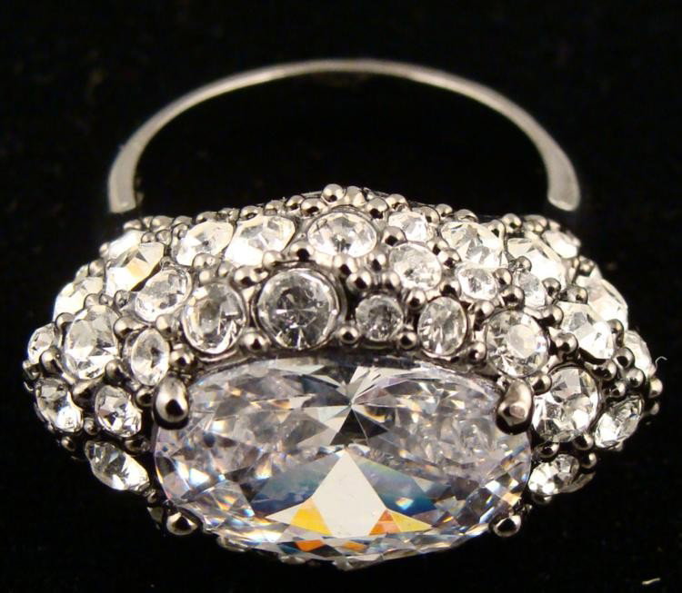 Givenchy Glamorous Crystal Cocktail Ring Size 7: This Cocktail Ring from Givenchy has a large faceted crystal at the center surrounded by round-cut crystals. The pewter tone band is a size 7. Its condition is excellent. * This ring goes over the top