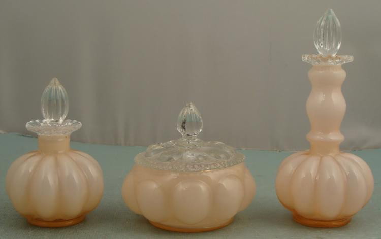 Fenton Glass 3 Pc Rose Melon Vanity Set 1940s: This 3 piece Vanity Set was made by Fenton in the 1940's. It is in the Rose Melon color, and includes two perfume bottles and one powder jar. The are complete with clear glass stoppers and lids. * Con