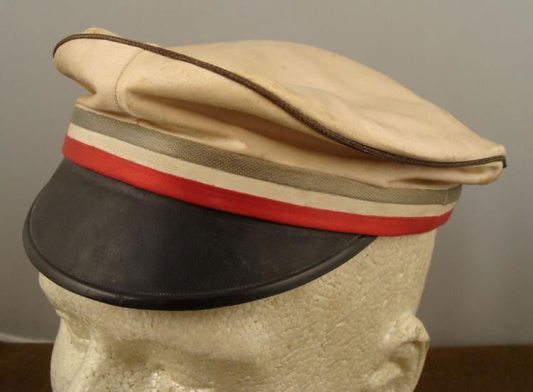 WWI German Military School Cap White Silk: This is a WWI era German Military School Cap. It is all white silk, with leather sweat band, red, white and gray rim, black brim, blue piping, and white silk lining. The maker name Jacob Sperb, is ins