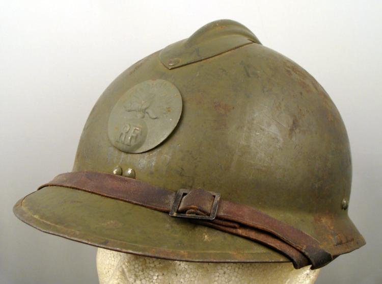 WWII French Adrian Helmet w/ Artillery Insignia: Here is WWII era French Adrian helmet with Artillery Insignia. The badge has a raised image with RF, and ridge across the top. There is a leather strap that goes across the brim. The interior has a le
