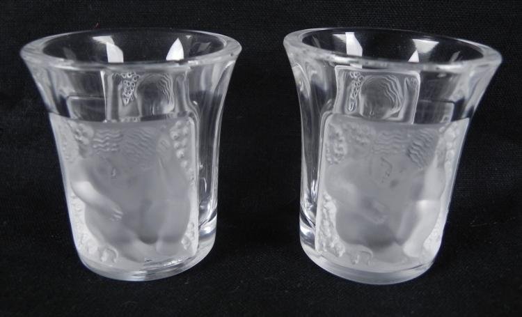 2 Lalique Signed Crystal Enfants Liquor Shot Glasses: Here are two Lalique crystal "Enfants" Liquor Shot Glasses. They feature angelic infants among a background of foliage. There is a Lalique signature on the bottom of each. They are 1 3/4 inches 