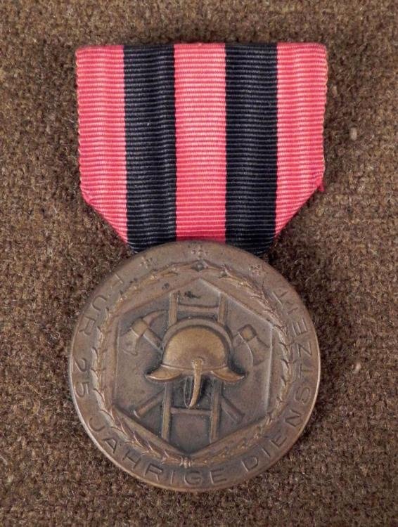 NAZI FIREFIGHTER'S 25 YEAR SERVICE MEDAL WITH RIBBON: HERE IS A NAZI FIREFIGHTER'S 25 YEAR SERVICE MEDAL THAT IS MOUNTED WITH A RIBBON. ON THE FRONT THERE IS A FIRE HELMET, WITH TWO AXES CROSSED AND A LADDER BEHIND IT, AND ON THE REVERSE IT READS FUR 25 