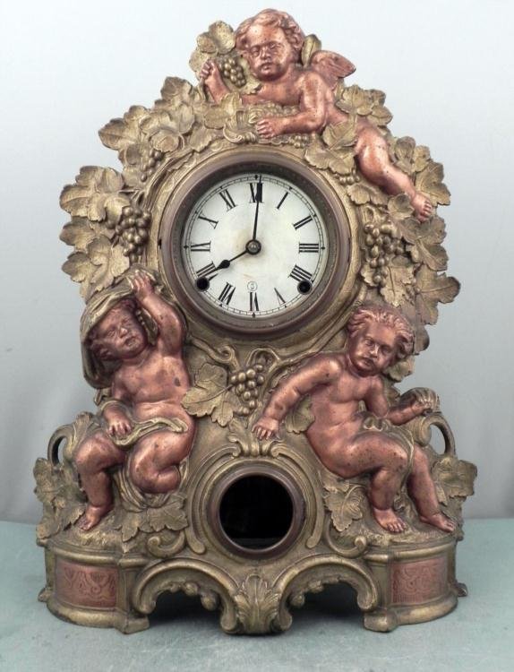 Waterbury Vintage Mantle Clock w/ Cast Cherubs: This is a Waterbury mantle clock with a gorgeous design, featuring gold painted vines and grapes, and copper painted cherubs. The front facade is cast iron, and the body that houses the clock me