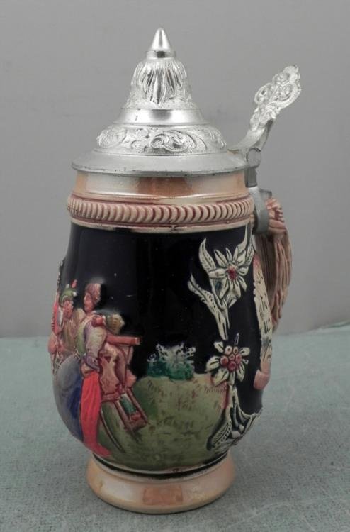 German Beer Stein Traditional Lidded Germany: This authentic German beer stein features a colorful relief scene of traditional merriment, and a lead tone lid. This jug is in excellent condition. The dimensions are 7 inches tall and 3 1/4 inches w