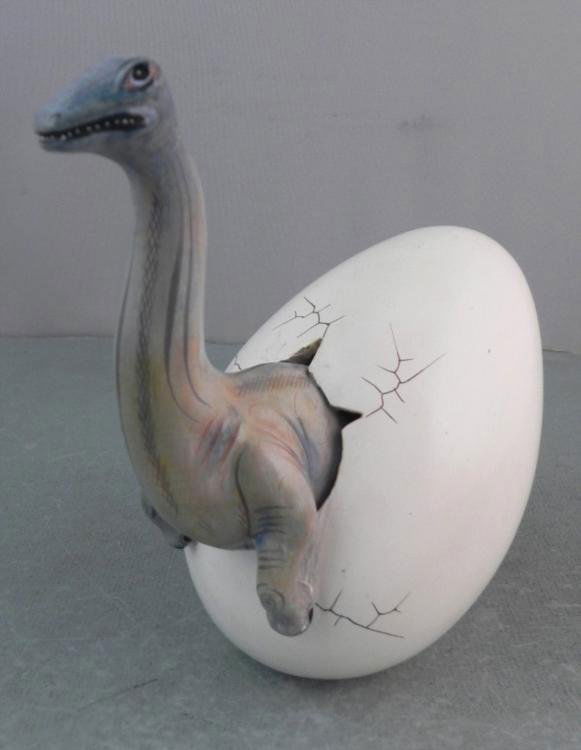 Baby Dinosaur Hatching Out Of Egg Sculpture Figurine: This baby dinosaur is hatching right out of an egg! This miracle of prehistoric birth is captured in this detailed sculpture, hand painted, and made in Mexico. It is about 7 1/2" tall. It appears to b